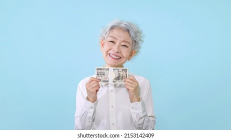 Asian senior woman with a wad of bills.