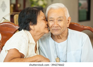 Asian Senior womman kissing senior man at home