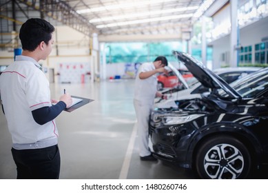 Asian Service Personnel And Asian Car Mechanics Are Writing Logs For Car Damage In An Automobile Repair Center.- Car Service, Repair, Maintenance And People Concept