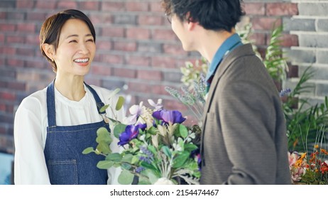 Asian Shop Clerk And Man Talking In Flower Shop.