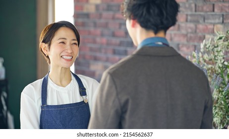 Asian Shop Clerk And Man Talking In Flower Shop.