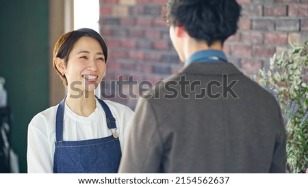 Asian shop clerk and man talking in flower shop.