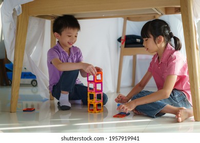 Asian Sibling Playing Building Block While Sitting In A Blanket Fort In Living Room At Home For Perfect Hideout Away From Their Other Family Members And For Them To Play Imaginatively.