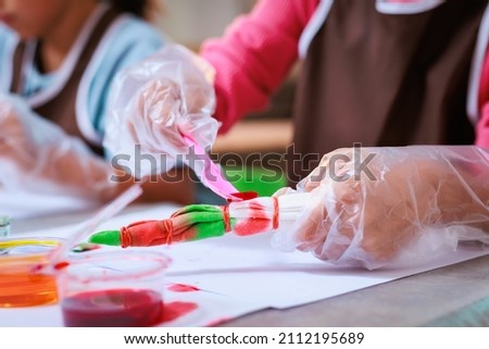 Asian siblings child girl enjoy making tie dye cloth together at home. Art and craft DIY for children concept.