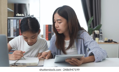 Asian siblings doing homework on a table at home - Powered by Shutterstock