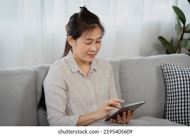 Asian Single Mom, Shopping Online, Through The Laptop He Held In Hand, He's So Focused On The Online Stuff He's About To Buy,  Hand Continued To Scroll Through The Viewing Tablet.