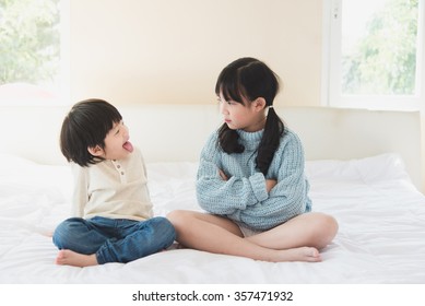 Asian Sister And Brother Quarreling On White Bed