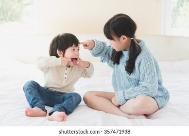 Asian Sister And Brother Quarreling On White Bed