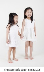 Asian Sisters Holding Hand On Plain Background