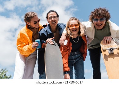 Asian Skater Grimacing Near Cheerful Friends Having Fun Outdoors