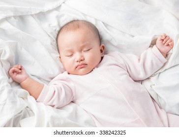 Asian Sleeping Baby On Back On White Bed