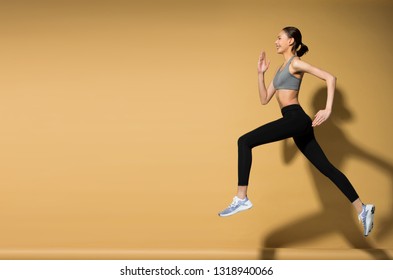 Asian Slim Fitness Woman Exercise Warm Up Stretch Spring Jumps Legs, Studio Lighting Yellow Beige Mustard Background Sun Shadow Copy Space, Concept Woman Can Do Athlete Sport 6 Packs