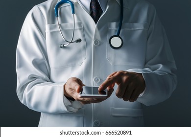 Asian Smart Doctor Holding Smartphone Computer With Hand. Surgeon Has Stethoscopes. Concept Of Medical Live In Social Online.