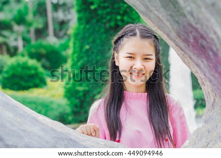 Asian smiling little girl sitting in the park.