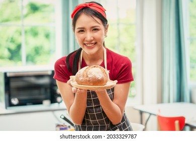 Asian smiling young female chef present bakery bread from online class in kitchen , Bakery online class concept - Powered by Shutterstock