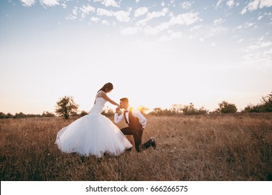 Asian smiling young newly married wedding couple on walk in dry lawn. Groom bride laughing in beautiful white dress. Relationship love concept. Man kiss hand woman on nature outdoors. Wedding concept.