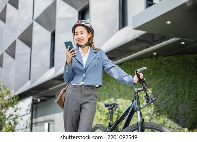 Asian Smiling Young Woman With Helmet Hold Mobile Smart Phone Talk With Business During Go To Office Work At Street With Bicycle, Eco Friendly, Lifestyle Business Female Commuting Outside In Morning