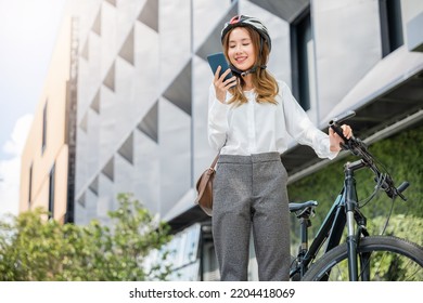 Asian Smiling Young Woman With Helmet Hold Mobile Smart Phone Talk With Business During Go To Office Work At Street With Bicycle, Eco Friendly, Lifestyle Business Female Commuting Outside In Morning