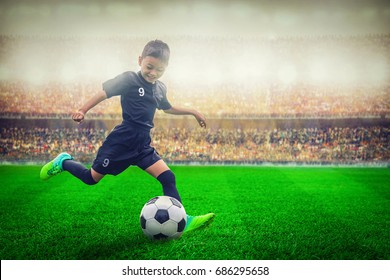 Asian Soccer Kid Kicking Football In The Stadium