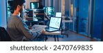 Asian software developers working on multiple screens displaying code and application diagrams at night in modern office
