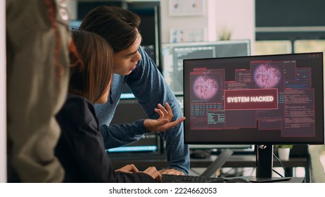 Asian software programer having system crash hacking problem with security breach warning, writing code on multiple screens. Showing critical error message and hacked pc server. Handheld shot.