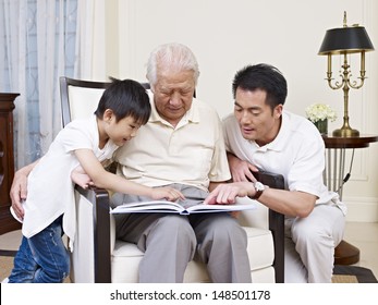 Asian Son, Father And Grandfather Reading A Book Together.