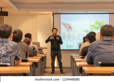 Asian Speaker Is Speaking On The Stage Over The Presentation Screen In The Education Seminar