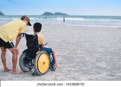Asian special child on wheelchair and his dad on the beach at sunset, Father helped him to get closer to nature, Life in the education age of disabled children, Happy disabled kid concept.