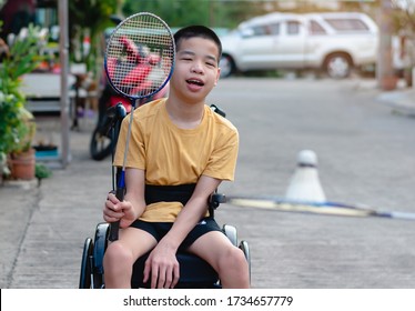 Asian Special Child On Wheelchair Is Playing Badminton To Strengthen Muscles In The House, Lifestyle Of Disabled Child,Life In The Education Age Of Children, Happy Disability Kid Stay At Home Concept.