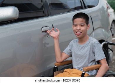 Asian Special Child On Wheelchair Catch The Car Door Going Up On A Car Parked In A Disabled Parking Space, Life In The Education Age Of Disability Children,Happy Special Need Kids Concept.