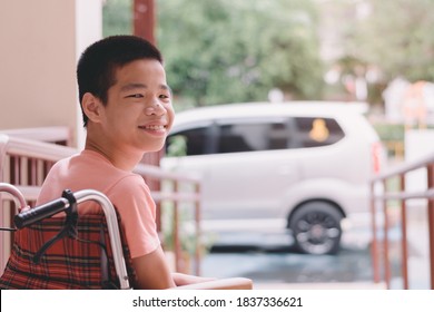 Asian Special Child On Wheelchair Waiting The Car On Ramp For Disabled People In Parking Space, Life In The Education Age And Public Transport Of Disability Children,Happy Special Need Kids Concept.