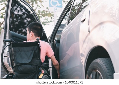 Asian Special Child On Wheelchair By The Car Door Going Up On A Car Parked In A Disabled Parking Space, Using A Disabled  Children Vehicle, Happy Special Need Kids Concept.