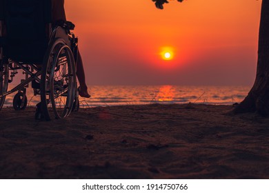 Asian Special Child On Wheelchair On The Sea Beach With Sunset On Travel Time In Holiday Family And Learning About Nature Around The Sea,Lifestyle In The Education Age Kids,Happy Disabled Kid Concept.