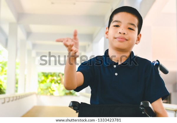 Asian special child on wheelchair is\
pushing his car on the ramp for the disabled., Life in the\
education age of children, Happy cerebral palsy kid\
concept.