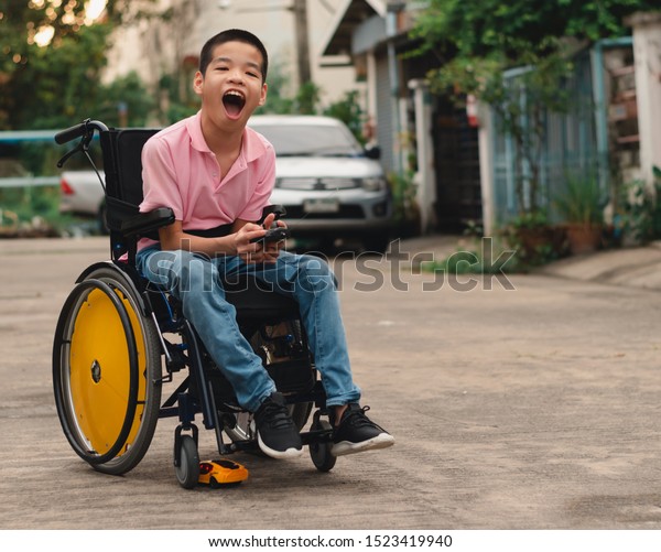 Asian special child on wheelchair\
is playing a radio car forced on the road, Life in the education\
age of disabled children, Happy disability kid\
concept.
