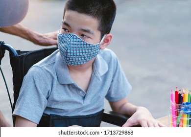 Asian Special need child on wheelchair wearing a cotton mask by parent, The boy doing home work, Study and Working at home for safety from covid 19, Life in education age of disabled children.
