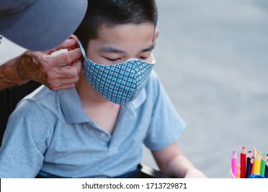 Asian Special Need Child On Wheelchair Wearing A Cotton Mask By Parent, The Boy Doing Home Work, Study And Working At Home For Safety From Covid 19, Life In Education Age Of Disabled Children.