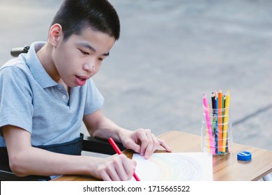 Asian Special Need Child On Wheelchair Enjoying Training Of Hand And Finger Muscles Through Drawing Us Large Wooden Sticks, Special Children's Lifestyle And Education Age, Happy Disabled Kid Concept.