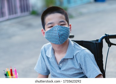 Asian Special Need Child On Wheelchair Wearing A Cotton Mask By Parent,The Boy Doing Home Work, Study And Working At Home For Safety From Covid 19,Life In Education Age Of Palsy Kid,Social Distancing.