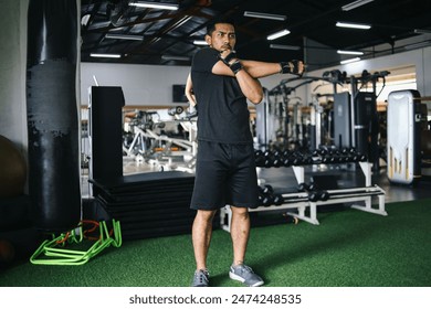 Asian sport man in black sportswear stretching arms with cross-body shoulder stretch pose and warming up before weight training in fitness gym.  - Powered by Shutterstock