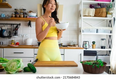 Asian Sports Woman Eating Healthy Green Salad In New Kitchen