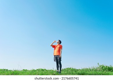 Asian Sportsman Drinking Under The Clear Sky