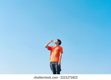 Asian Sportsman Drinking Water Under The Clear Sky