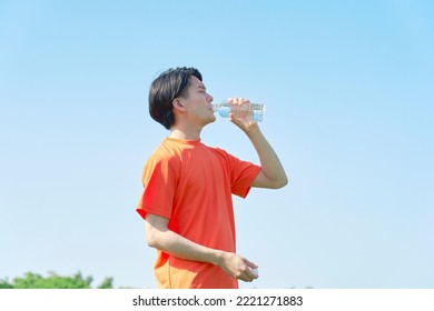 Asian Sportsman Drinking Water Under The Clear Sky