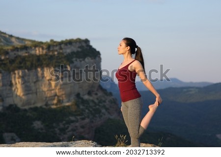 Asian sportswoman stretching leg standing in the mountain