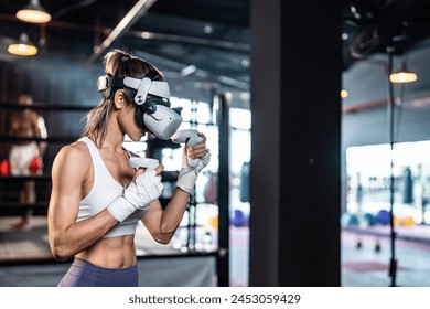 Asian sportswoman using innovative technology VR glasses for exercise. Attractive beautiful girl wearing virtual reality headset and hold gaming controller while doing boxing fight workout at fitness. - Powered by Shutterstock