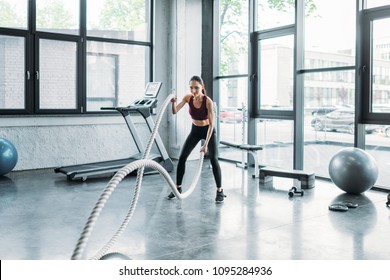 Asian Sportswoman Working Out With Battle Ropes At Gym