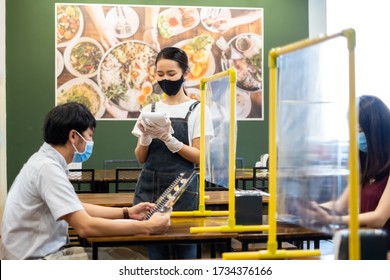 Asian Staff Restaurant Waitress Wear Protective Face Mask Working In The Restaurant With Social Distancing To Protect Infection From Coronavirus Covid-19