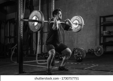 asian strong athletic man having workout and bodybuilding with barbells weight front squat setting style in gym and fitness club in black and white