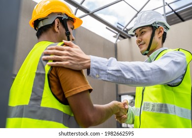 Asian Structure Engineer And Worker Making Handshake On Building Working Site. All People Wearing Safety Hardhat During Walking In Construction Workplace. Business Deal, Merger And Acquisition Concept